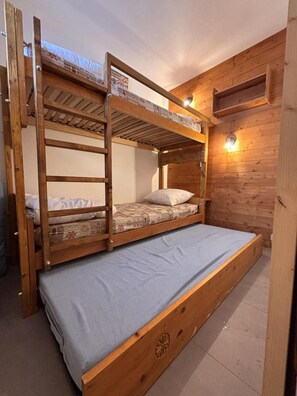 Ein Stockbett mit einer unteren Liege, einem Kopfteil und einer Wandleuchte.