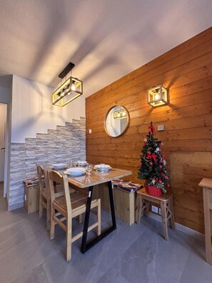 Ein Essbereich mit Holztisch und -stühlen, einem Weihnachtsbaum und einer Steinwand.