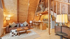 Ein Holzblockhaus-Interieur mit Sofa, Couchtisch und Essbereich.