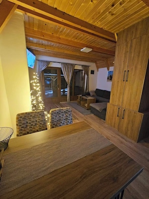 A wooden interior with a dining table, chairs, a sofa, and a cabinet.