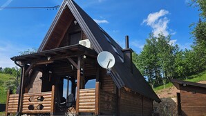 A wooden cabin with a sloped roof, a satellite dish, and a gravel driveway.