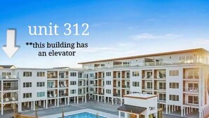 A multi-story building with a pool, balconies, and a sign indicating 'unit 312'. -  Atlantic's Edge @ Carolina Beach—Panoramic views of the ocean + pool /hot tub (Carolina Beach)