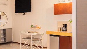 A compact kitchen with a dishwasher, a small dining table with chairs, a TV mounted on the wall, and pendant lights above the counter. - Style and comfort studio/2 Guests/Ac/Private (Oaxaca de Juárez)