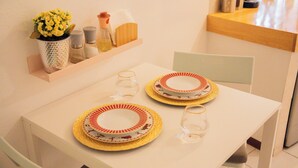 A dining table with two plates, two glasses, a vase with yellow flowers, and a salt and pepper set on a shelf. - Style and comfort studio/2 Guests/Ac/Private (Oaxaca de Juárez)