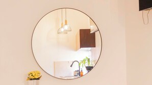 A room with a round mirror, a cabinet with shelves, an air conditioning unit, and a hanging light fixture. - Style and comfort studio/2 Guests/Ac/Private (Oaxaca de Juárez)