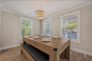 A dining area with a wooden table, benches, and a unique chandelier.