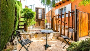 Eine Terrasse mit Steinböden, einem Holztisch, zwei Stühlen und einem Bambuszaun.