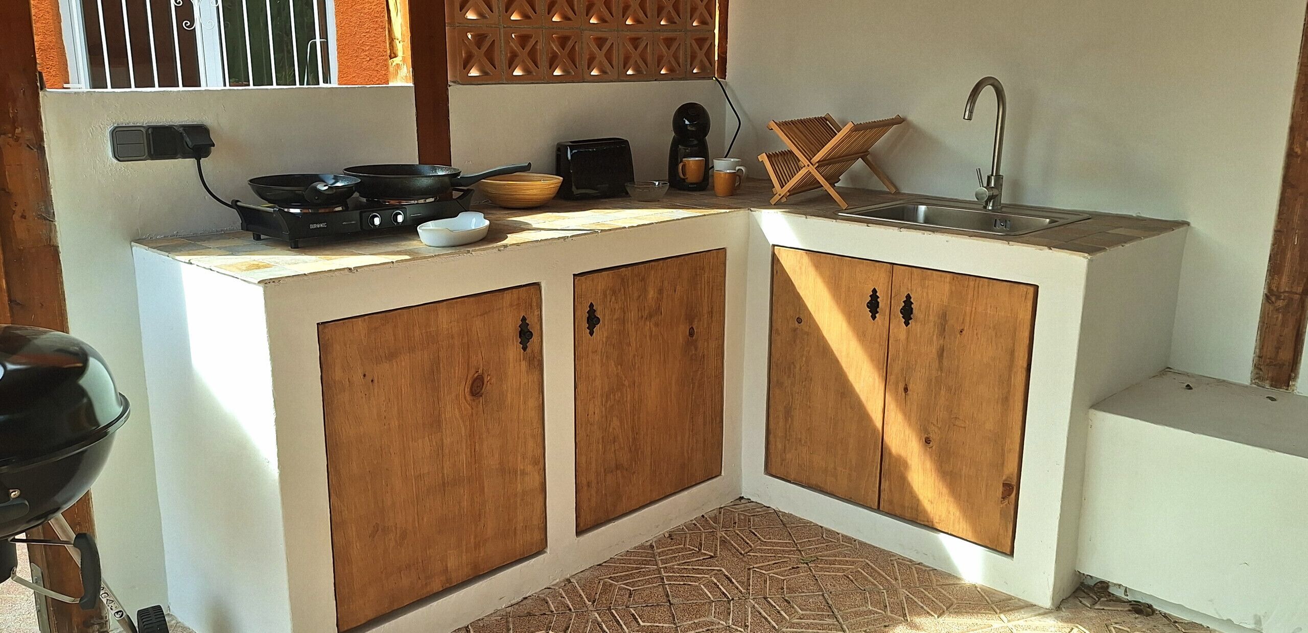 A compact kitchen with wooden cabinets, a gas stove, a coffee maker, and a sink.