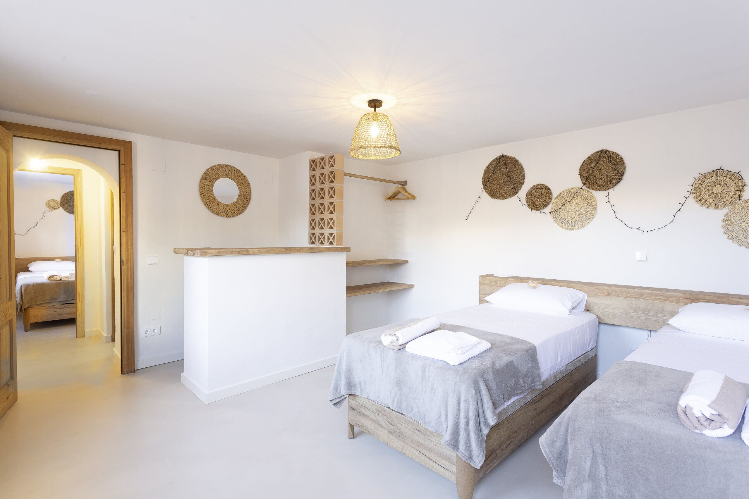 Habitación de hotel con dos camas, cabecero de madera, un escritorio pequeño y adornos en la pared.