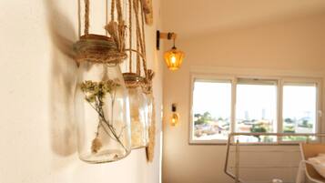 Una habitación con una lámpara colgante, una ventana con vistas y una estantería con frascos.