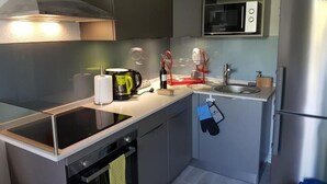 Una cocina funcional con microondas, horno y refrigerador de acero inoxidable.
