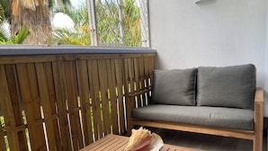 Una mesa de madera con una concha, un sofá gris y una valla de madera.