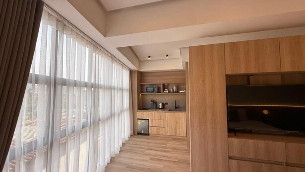 A modern kitchen with wooden cabinets, a microwave, and a coffee maker. - Autenthico X Atempo Local Hotel & Suites (Medellín)