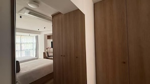 A bedroom with a bed, a wooden wardrobe, and a window with curtains. - Autenthico X Atempo Local Hotel & Suites (Medellín)