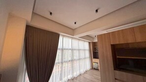 Una sala de estar moderna con un ventanal grande, suelo de madera y armarios empotrados de madera.