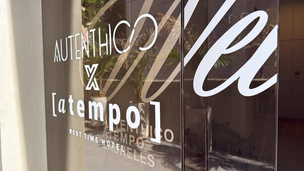 A hotel window with the name 'Authentico' and 'Atempo' visible, indicating the hotel's name and possibly its brand or type. - Autenthico X Atempo Local Hotel & Suites (Medellín)