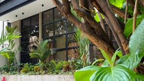 Un edificio moderno con amplios ventanales y un jardín con diversas plantas.