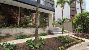 A modern building with large windows, a concrete planter with greenery, and a staircase leading to an upper level. - Autenthico X Atempo Local Hotel & Suites (Medellín)
