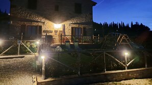 A stone building with a balcony, a parking sign, and a well-lit entrance. - Perfect retreat among the hills of Chianti Classico. Suitable for families and couples (Barberino Val D'elsa)