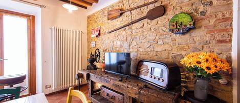 A rustic interior with a stone wall, wooden furniture, a vintage radio, and a television.
