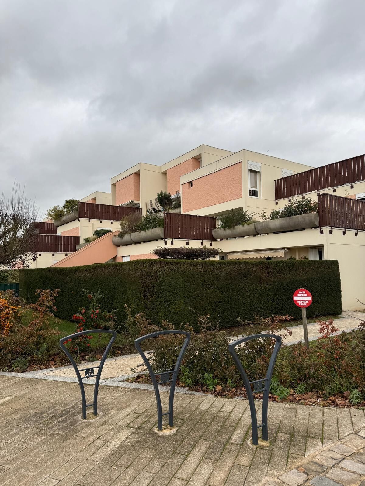 Un immeuble d’habitation doté d’un toit plat, d’une entrée sécurisée par un portail et d’un panneau indiquant que l’accès est limité.