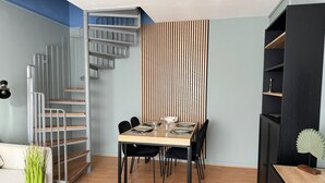 En matplats med ett träbord, svarta stolar och en vägg som består av vertikala träribbor.
