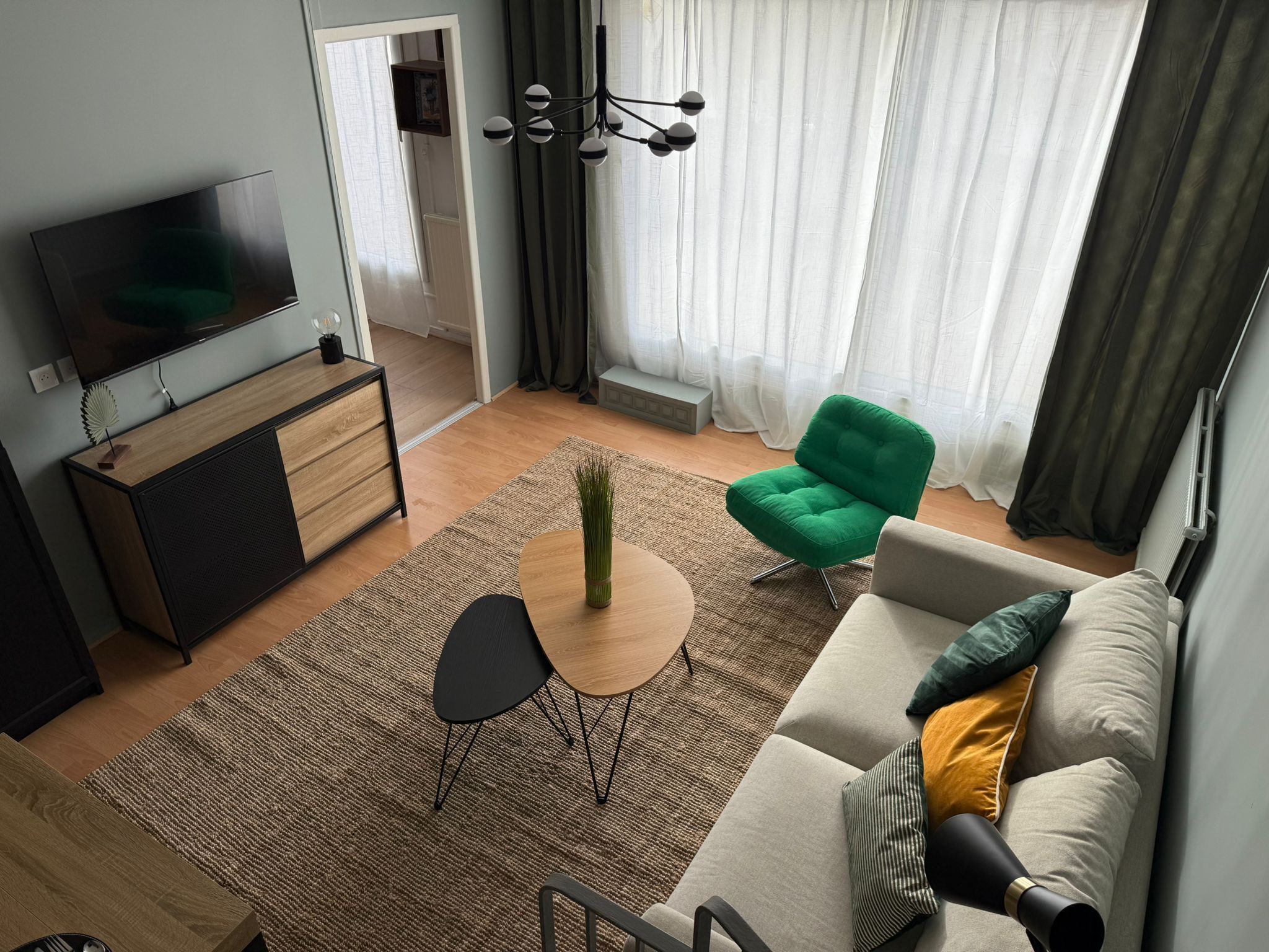 Un salon moderne avec un téléviseur, un canapé, des fauteuils et une petite table.