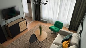 Ett modernt vardagsrum med en TV, en soffa, stolar och ett litet bord.