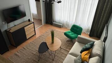 Un salon moderne avec un téléviseur, un canapé, des fauteuils et une petite table.