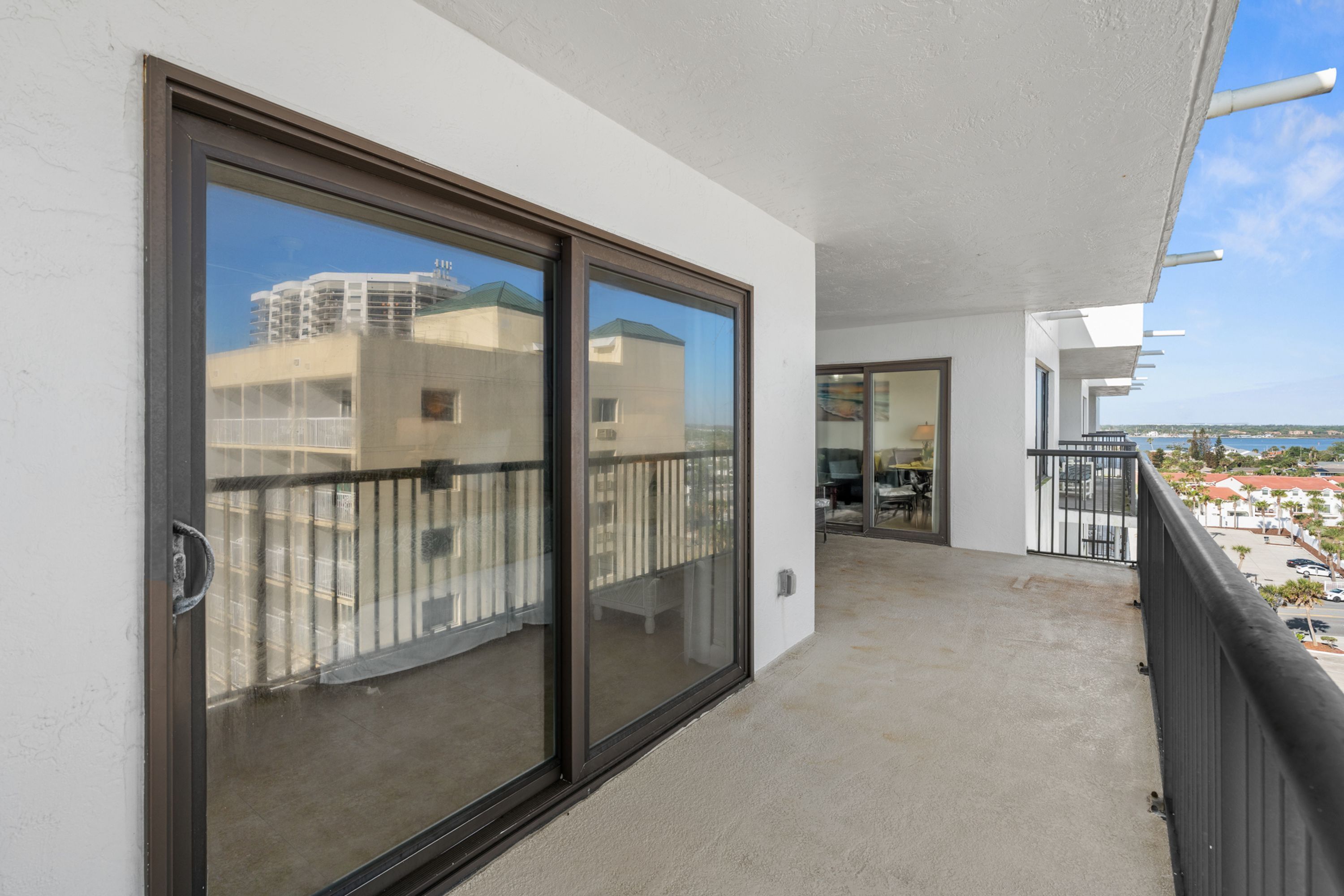 A balcony with a glass door, a view of buildings, and a clear sky.