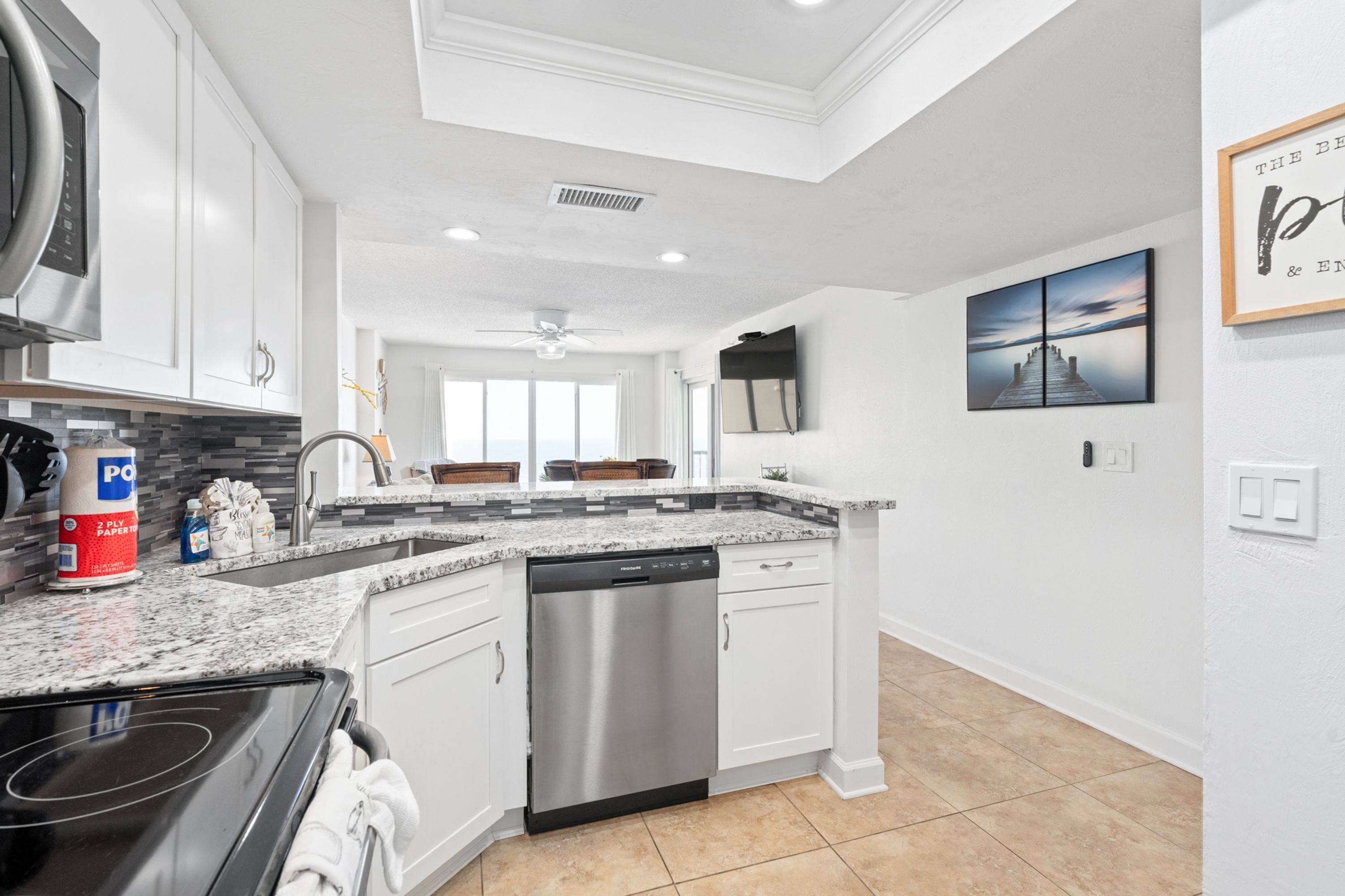 A modern kitchen with white cabinets, a stainless steel dishwasher, and a granite countertop.