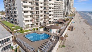 Un hotel con piscina en la azotea, tumbonas y vista al mar.