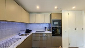 Eine moderne Küche mit Spüle, Herd, Backofen und Schränken.