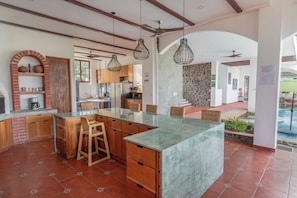 A spacious kitchen with a large island, wooden cabinets, and hanging pendant lights.