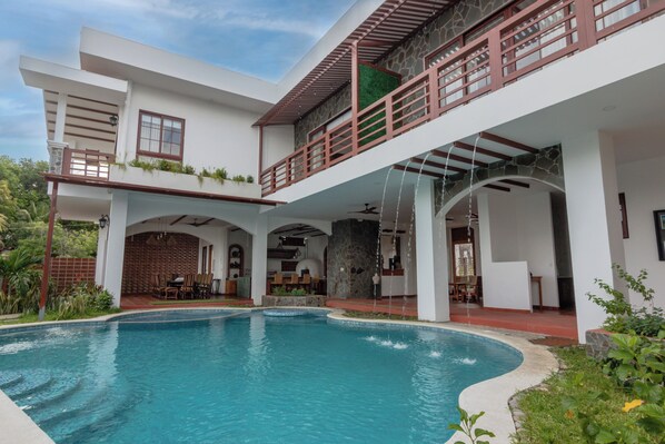 A modern house with a swimming pool, outdoor seating, and a balcony.