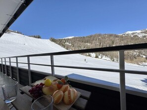 A balcony with a view of a snowy mountain, a table with fruits, and a glass. - 100m from resort center, 4th floor, view mountain, balcony, tv, ski locker, 16m², Vars (Vars)