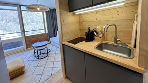 Een moderne keuken met een houten aanrecht, een gootsteen en een eethoek met een tafel en bank.