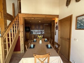 A dining area with a wooden table, chairs, and a view into a kitchen with wooden cabinets. - 200m from shops, 1st floor, balcony, tv, ski locker, 90m², Les Saisies (Villard-sur-Doron)