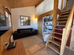 A wooden interior with a staircase, a sofa, and a small table. - 200m from shops, 1st floor, balcony, tv, ski locker, 90m², Les Saisies (Villard-sur-Doron)