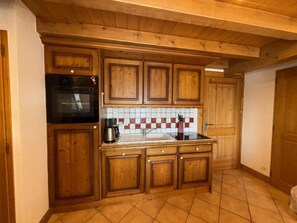 A kitchen with wooden cabinets, a tiled backsplash, and a black oven. - 200m from shops, 1st floor, balcony, tv, ski locker, 90m², Les Saisies (Villard-sur-Doron)