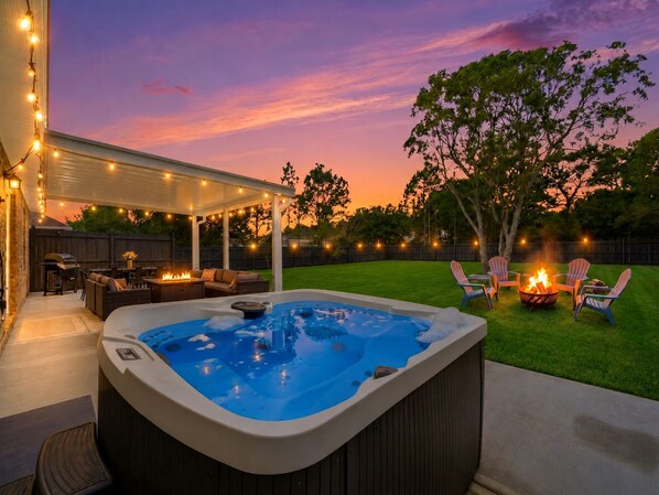 Ein Garten mit Whirlpool, Gartenmöbeln und Lichterketten.