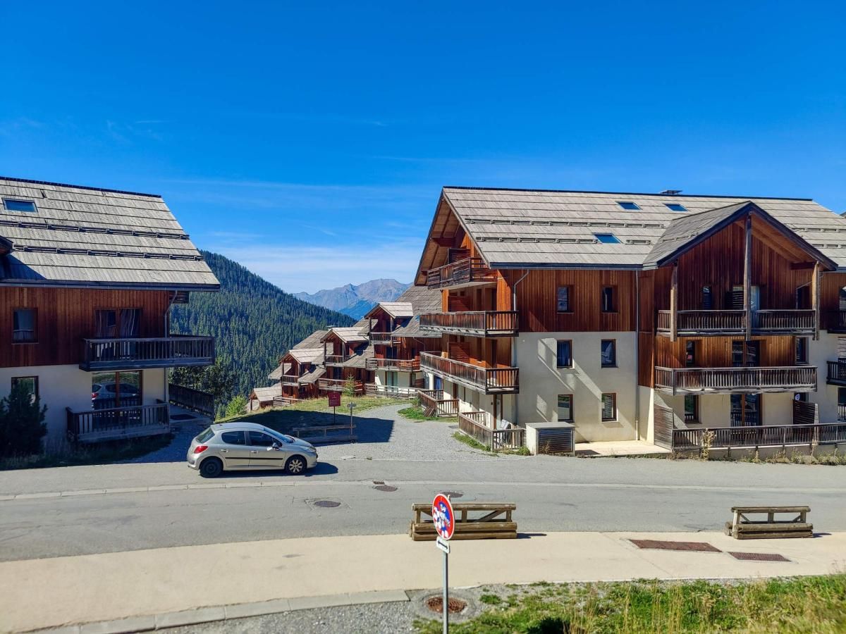A mountain resort with wooden buildings, a car parked in front, and a clear sky.