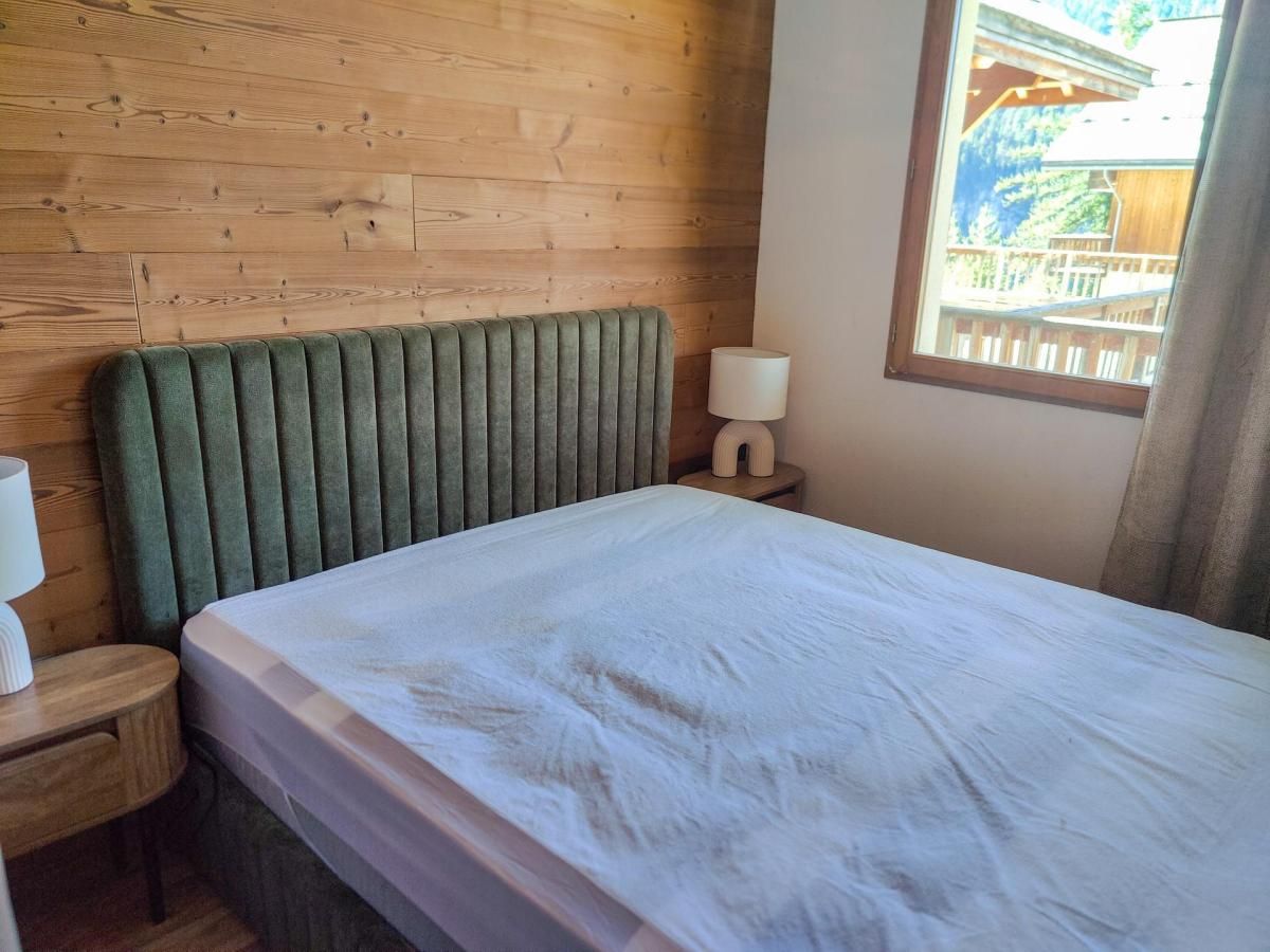A room with a bed, a nightstand, a lamp, and a window with a view.