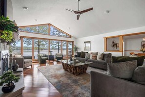 A spacious living room with a large window, a ceiling fan, and a modern coffee table.