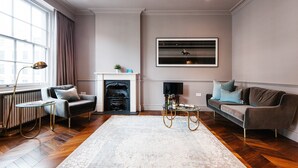 A living room with a fireplace, a sofa, a coffee table, and a television mounted on the wall. - The Cleveland Arms II (London)