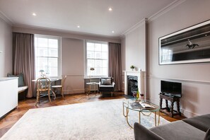 A spacious living room with a fireplace, a dining area with a table and chairs, and a sofa. - The Cleveland Arms II (London)