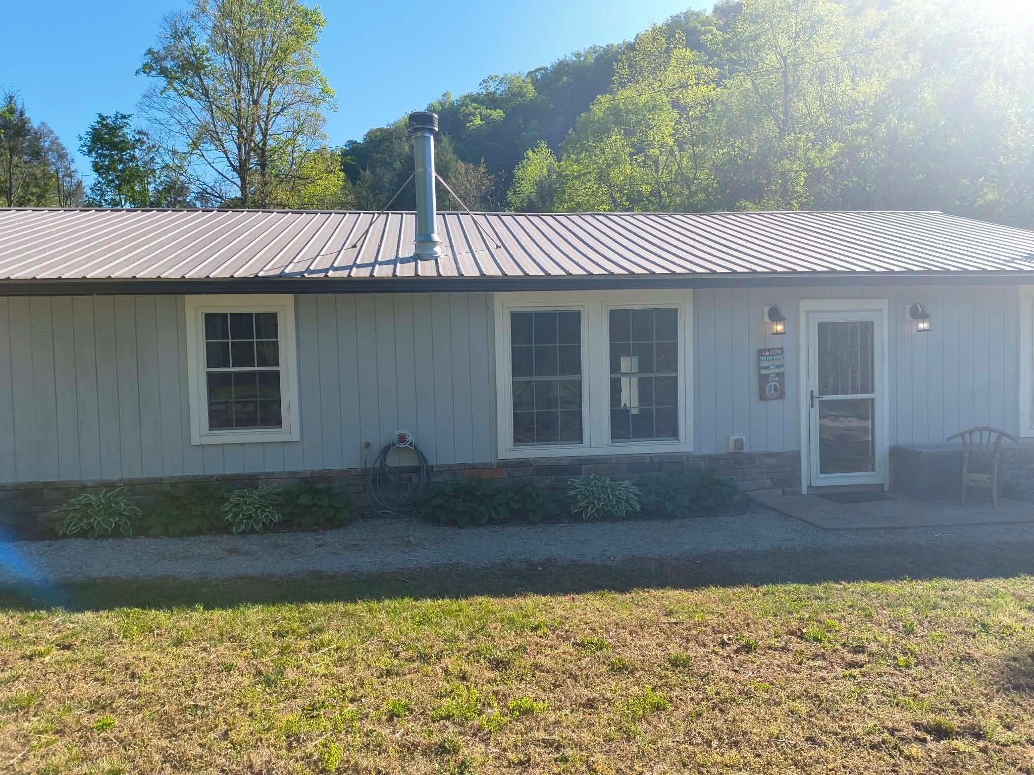 A small, single-story building with a metal roof, a front door, and a window.