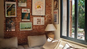 Una habitación con pared de ladrillo, una ventana grande, un sofá y varias imágenes enmarcadas.