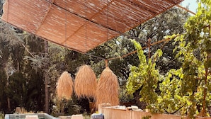 Un área de comedor al aire libre con piscina, sombrillas y una pérgola.
