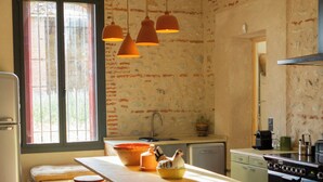 Una cocina con una isla central, taburetes de bar, un refrigerador, una estufa y lámparas colgantes.